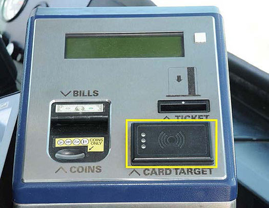 This is a photograph of the front view of the automated farebox. At the top of the farebox is a green and black digital display. On the lower left is a slot to insert bills and coins. On the right is the slot to insert a ticket just above a rectangular card target sensor.