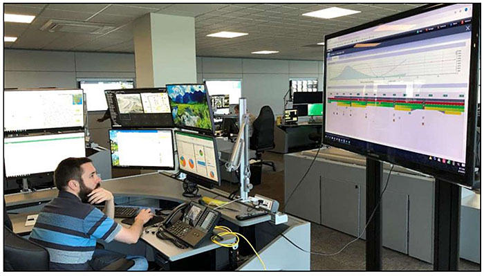 Photo of Ohio TMC operator at desk with multiple computers and screens showing various data, graphs, and information systems.