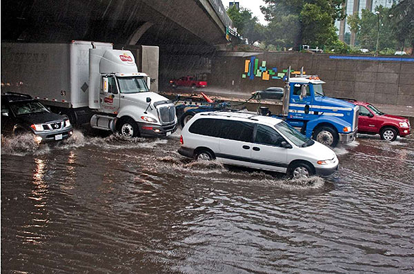 Authors relevant description: A photo shows vehicles moving in a flooded roadway is shown.