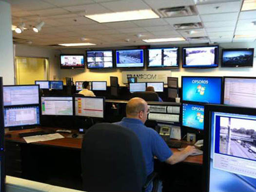 A photo of regional Transcom TMC. A man sits behind an array of computer monitors.