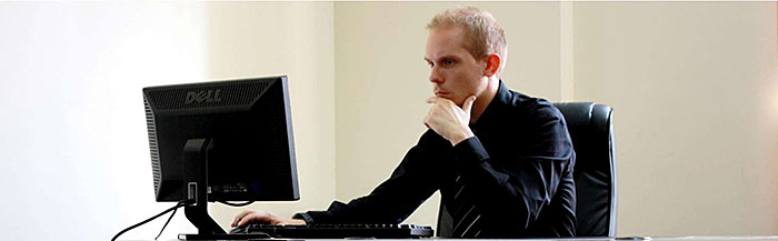 This slide shows a person at an office desk looking pensively at a computer monitor.