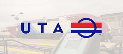 A photo of a card validator sitting on a train station platform. In the background, there is a commuter train and stair rails. Superimposed on the photo is the logo of the Utah Transit Authority, with the letters UTA and a red, white and blue symbol.