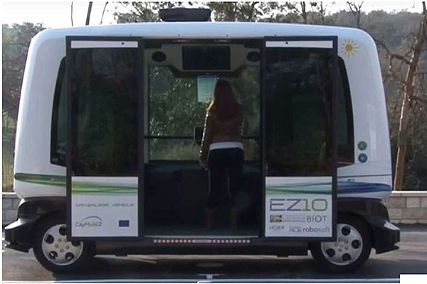 This slide shows a side view photo of the Easymile EZ10 vehicle with double doors open on the side.