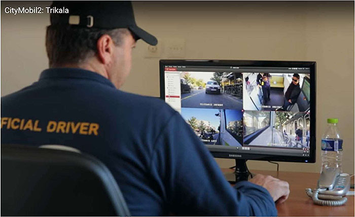 This slide shows a back view of a CityMobil vehicle operator with the words Official Driver on the back of his jacket. He is seated at a desk before a monitor screen showing four images from cameras in the vehicle.