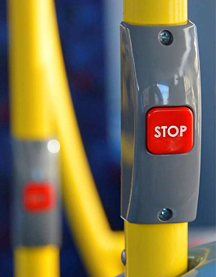 A photo of a Stop button on a handrail in a bus that is used to request a stop.