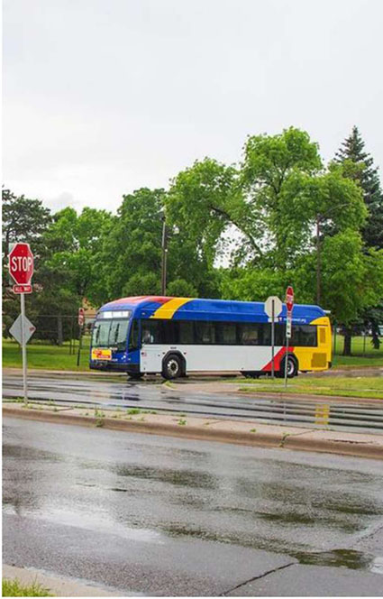 This slide is entitled, “Metro Transit”. There is a graphic on the left-hand side of a transit bus stopped at a stop sign in the rain.