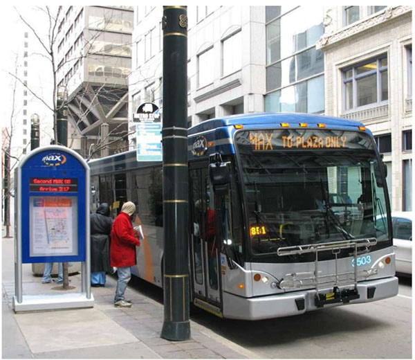This slide has a photo of a person boarding a Kansas City Area Transportation Authority (KCATA) MAX bus at a bus stop with a dynamic message sign that shows real-time information to the left of the person boarding the bus.
