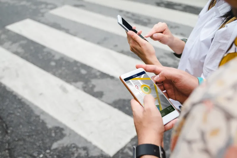 Traveler use map on mobile phone app to search for route location of place with gps on street when travel in city.