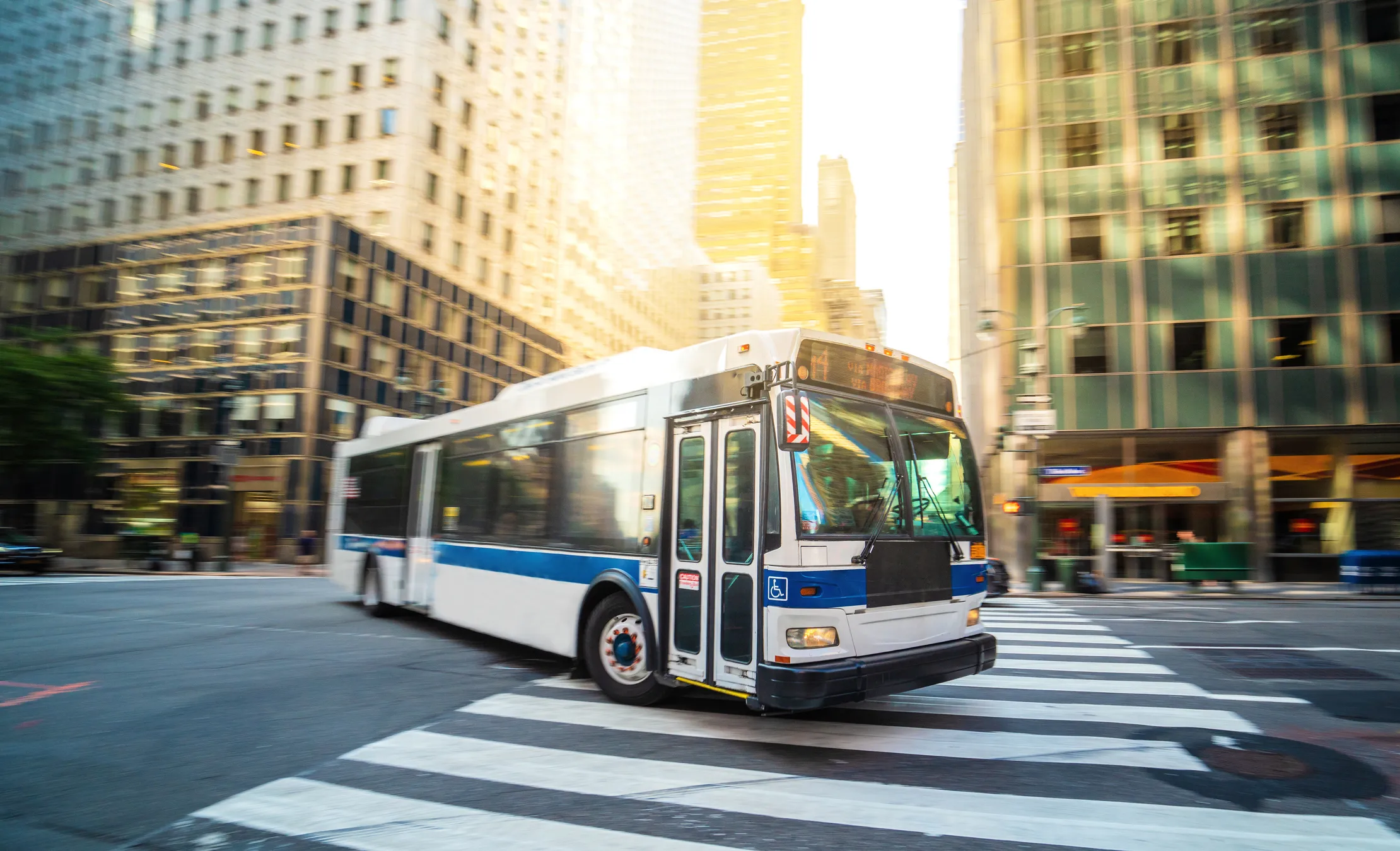 New York City public bus turning a corner in front of skyscrapers in Manhattan.