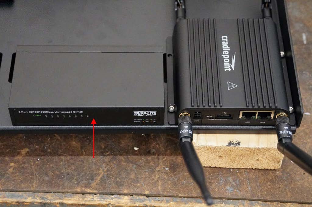 This photo shows the network switch to the left of the Cradlepoint router mounted on the component shelf. An arrow points to the network switch.