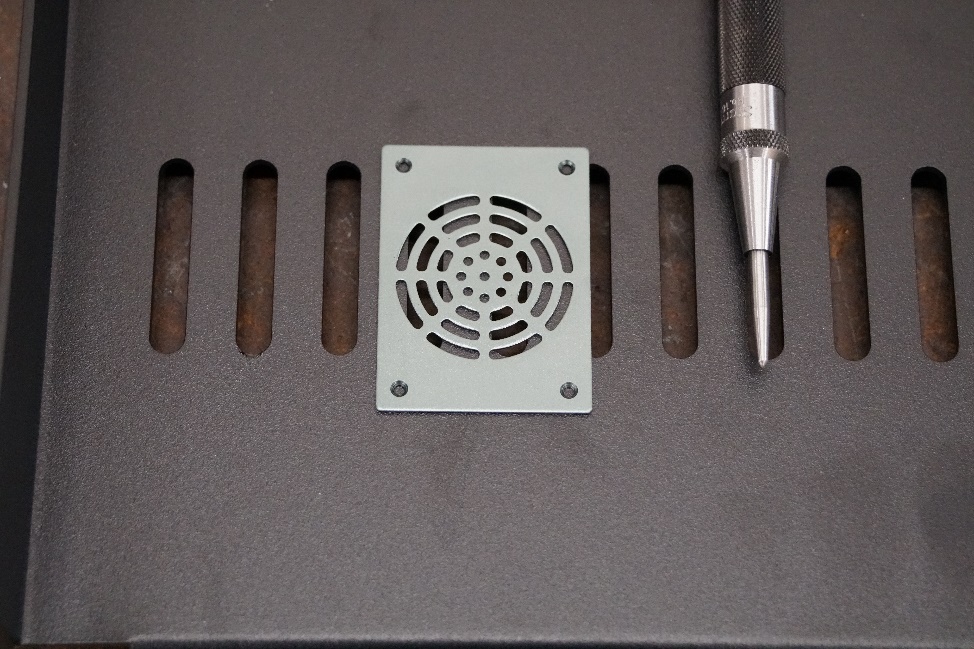 This photo demonstrates the fan cover placement on a component shelf. A center punch is to the right of the fan cover.