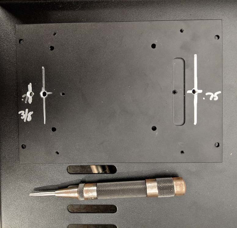 This photo shows the bottom plate of the NUC computer on the component shelf. A center punch is next to the plate.