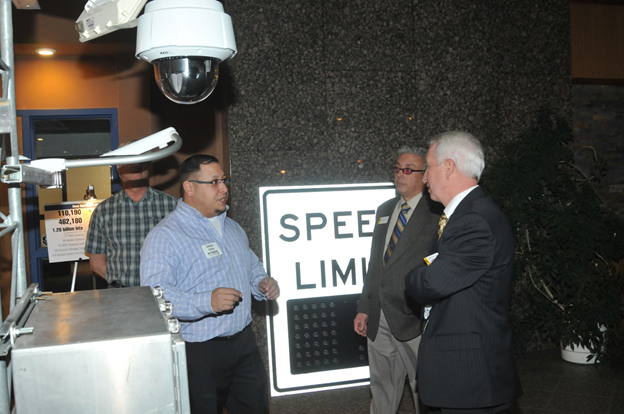 Dallas Ortiz, WYDOT ITS Technician, discusses roadside ITS devices, including Roadside Units, with visitors.