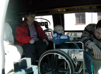 photo of a wheelchair-bound child getting strapped into a transportation van