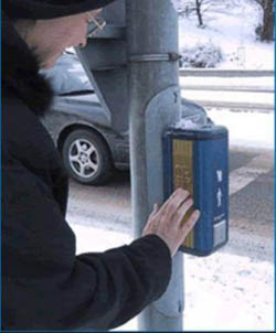 Photo of a pedestrian using an intelligent pedestrian signal. Photo courtesy of USDOT. All rights reserved.