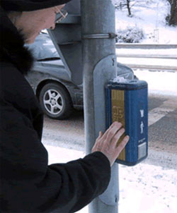 photo of a woman placing her hand on raised directional markings on a pedestrian crossing sign