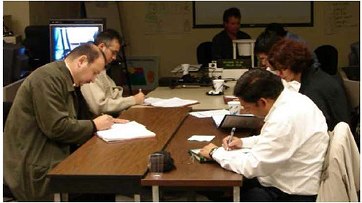 A photo of a group of engineers working at a table is shown on the right bottom.